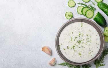 Tarator soup in a bowl with ingredients on a light stone backgro