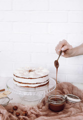 beautiful light composition on a white brick wall background: carrot cake with a hand and caramel