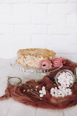 light composition on a white brick wall background: Napoleon cake with marshmallows