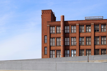 Exterior of old brick warehouse / office building. Light blue sky in background with room for copy. Freeway exit ramp in foreground. Cleveland, Ohio.