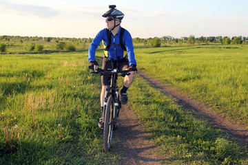 Fototapeta na wymiar cyclist on bike rides along the fields of wheat