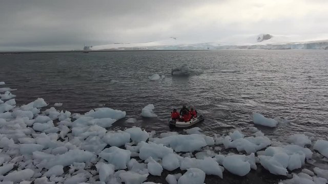 A rubber boat with tourists sailed to pieces of ice near the shore. Andreev.