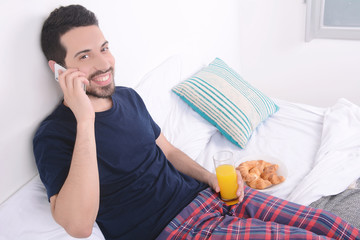 Man talking on phone in bed.
