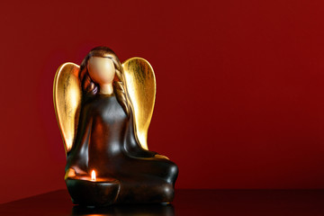 Angel figure candlestick on a bedside table with a burning candle in it