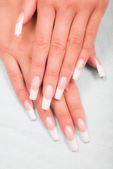 Naklejka premium Closeup of hands of a young woman with french manicure on nails against white background