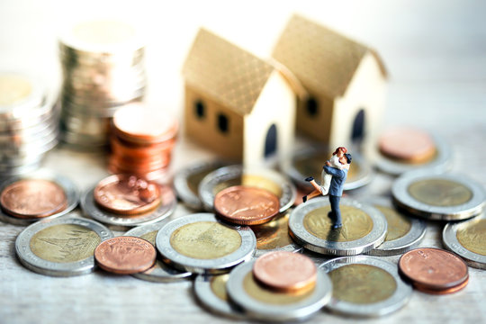 Miniature People Happy Couple Standing with Stack Coins White Background and Tiny Model House
