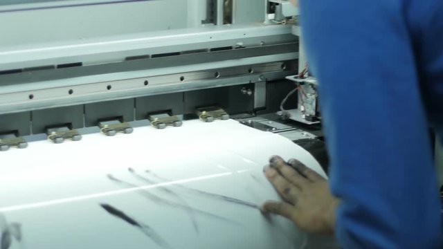 Backside View Man in Uniform Controls Wide Format Printer