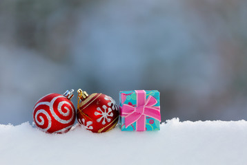 Colorful Christmas ornaments on white snow with blur background