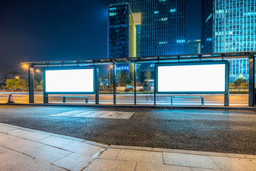 Blank billboard on bus stop at night.