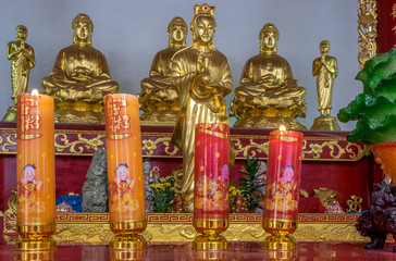 Candles and golden statues at Buddhist temple in Bangkok Thailand