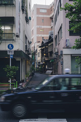 Taxi passing in front of narrow alley with traditional building downtown Tokyo, Japan