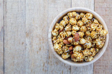 Popcorn caramel mix macadamia and almond taste on wood table with copy space. top view.