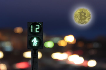 Pedestrian green traffic light at night with the timer on the background coin bitcoin instead of the moon shining brightly over a city at night.