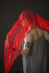 Young woman in silver dress with red scarf.