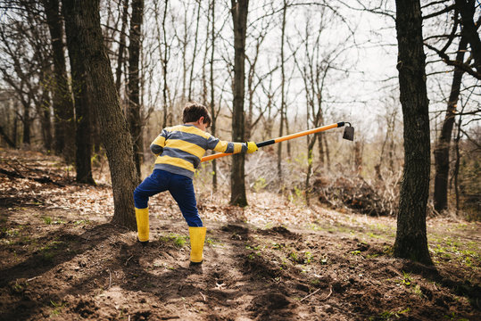 Boy in a garden digging soil with a hoe