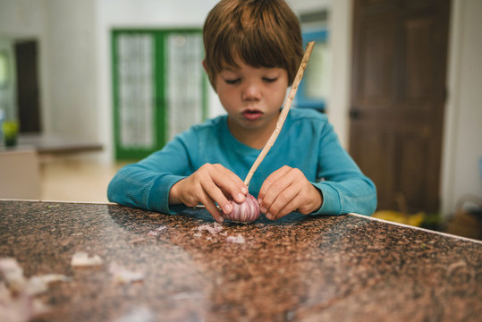 Boy peeling a fresh garlic bulb