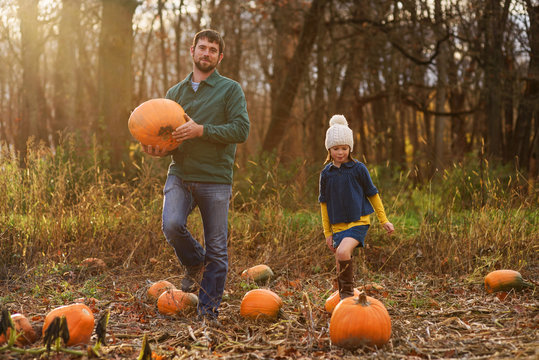 Father and daughter picking pumpkins in a pumpkin patch
