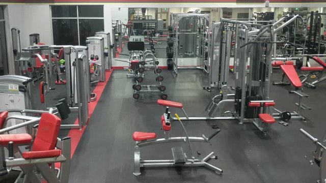 Empty gym facility with exercise equipment, weights, medicine ball racks shot at night.