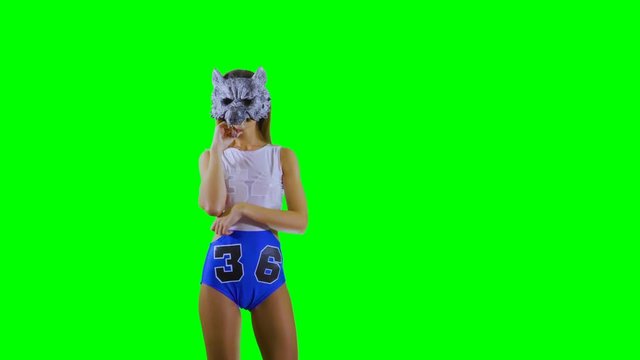 Girl in wolf mask thinks about something and show thumb up at green background