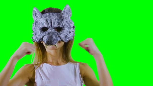 Gilr wearing wolf mask scratches at green background