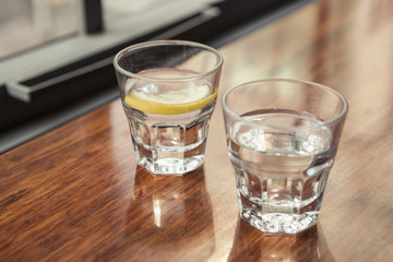 water and lemon with cup(glass) on the wood table.