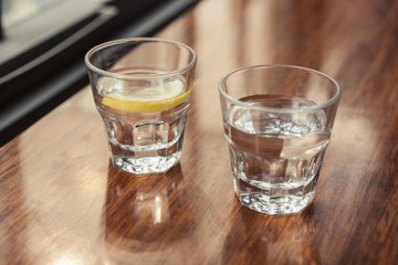 water and lemon with cup(glass) on the wood table.