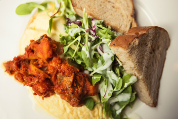 omelet with spicy chicken with bread on the white dish.