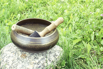 Tibetan Singing Bowl with wooden mallets  on a wood and grass background. Top view composition. Photo with vintage toning.
