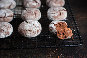 Deliciouse Homemade Chocolate crinkle cookies with powdered sugar icing grate for cooling on dark stone table background. Top view