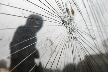 At the bus stop broken glass. There are a lot of cracks. On the background of the silhouette of a...