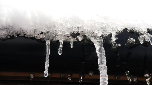 winter weather - snow and icicles dripping from roof gutter