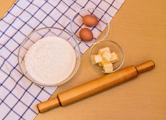 Flour, eggs, butter and rolling pin on table