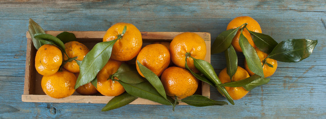 Fresh tangerines in an old box with leaves