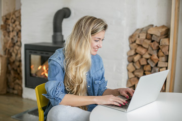 Young beautiful woman works for a computer from a home with a laptop on a white desk as a freelancer