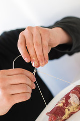 Close up of man's hands filling, rolling and tying together thinly sliced, raw beef roulades or Rouladen, a traditional German and Bavarian Sunday roast, filled with mustard, bacon, pickles and onions