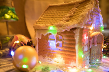 Handmade gingerbread house in luminous garland in the background of christmas decoration