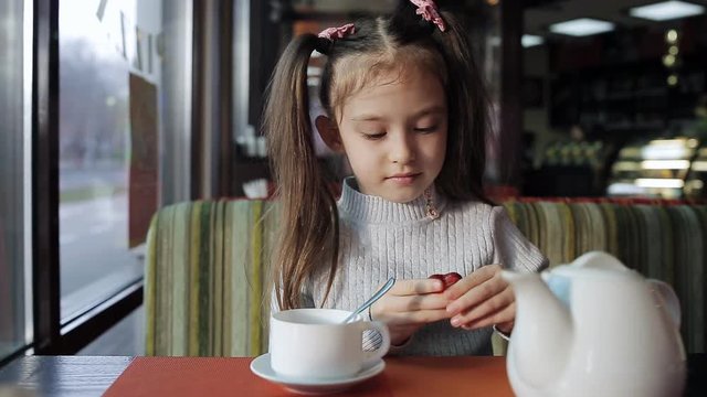 beautiful Little girl is having lunch in a cafe. baby girl eats candy and flavored tea