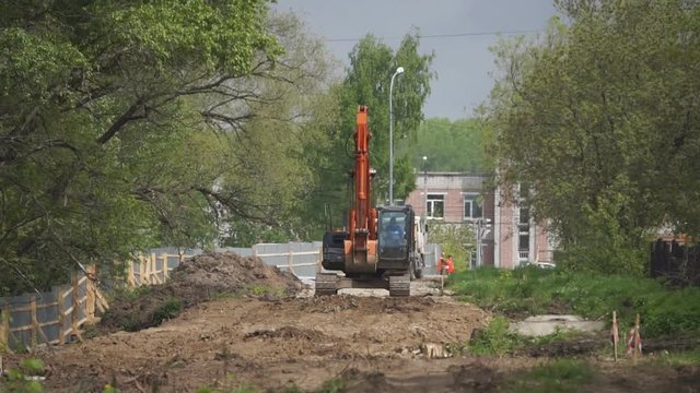 crawler excavator rides across clay heap and starts digging - dike construction - on camera