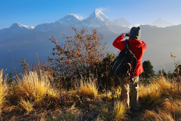 Tourist, a man, makes photo of Annapurna mountain with his mobile phone from Poon Hill, famous view point in Himalaya range at sunrise, Annapurna Circuit Trek, Annapurna Himal, Himalaya, Nepal, Asia