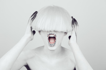 A girl with white skin and a white wig with an inscription on her lips 'surreal'.