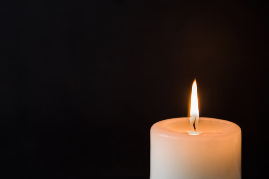 Candle with flame on the dark background. Condolence and religion concept. Empty place for a text.