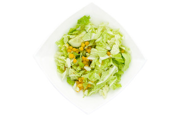 Vegetable salad of cabbage, corn and cucumber in the white plate isolated