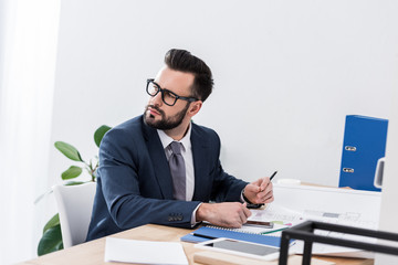 thoughtful businessman sitting at working table and looking away