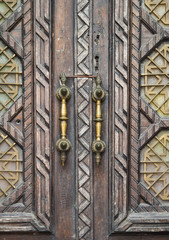 Door handles on a wooden door with carved ornaments