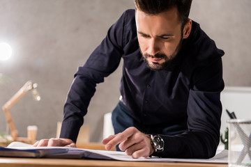 handsome architect looking at blueprints on table