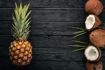 Coconut and pineapple on a wooden background. Tropical fruits and nuts. Top view. Free space for text.