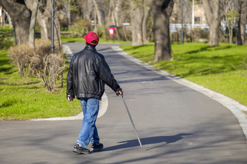 A man with a cane is walking in the park