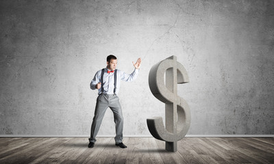 Determined banker man in empty concrete room breaking dollar figure