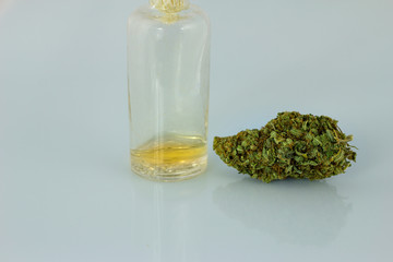 Medical Oil Cannabis - transparent glass apothecary bootle with oil and marijuana flowers on the white background.
