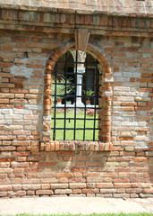 medieval Window with metal grating in the middle of the brick wa